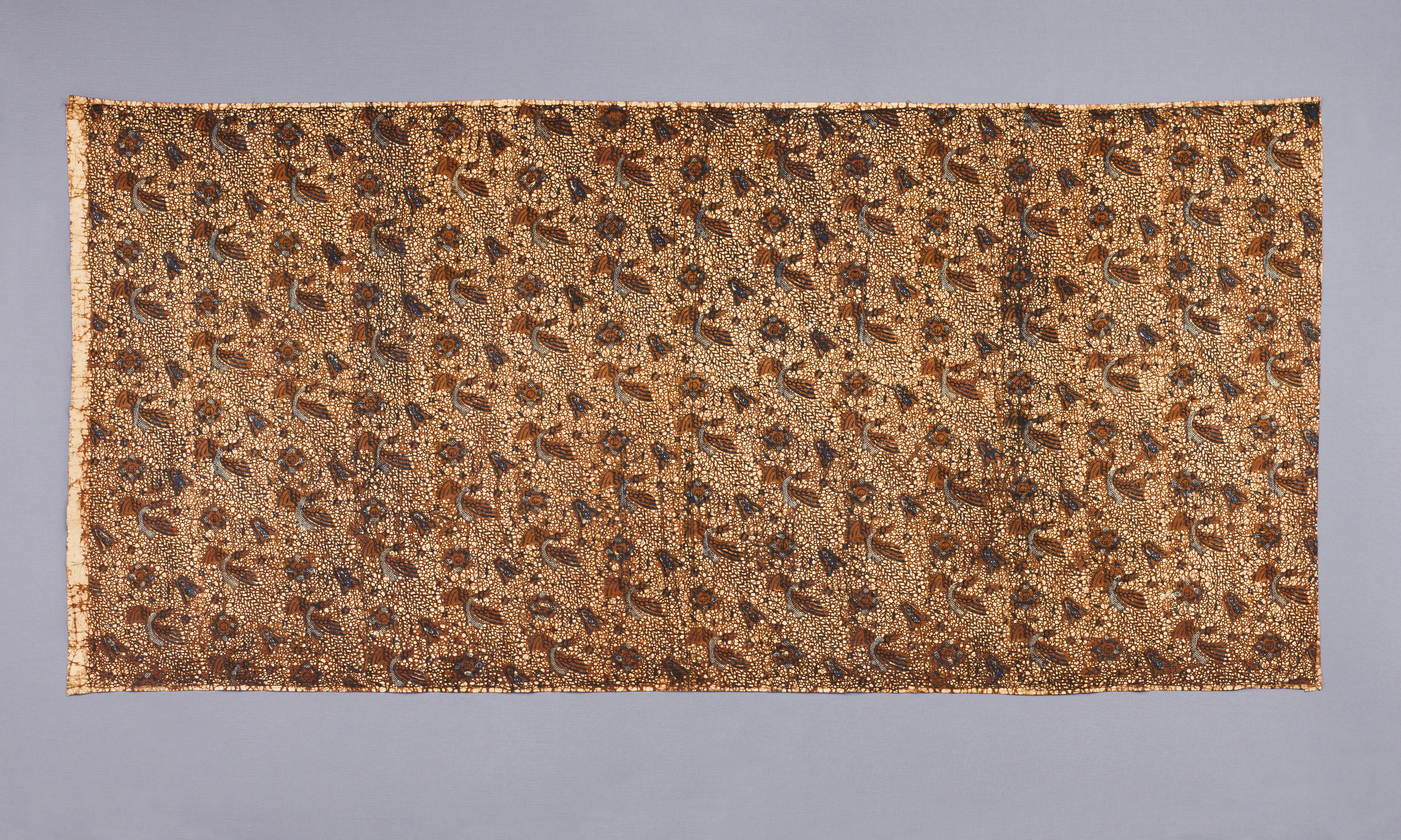 A flat rectangular Javanese batik hip wrapper with repeating dark bird and floral motifs on a warm cream ground.