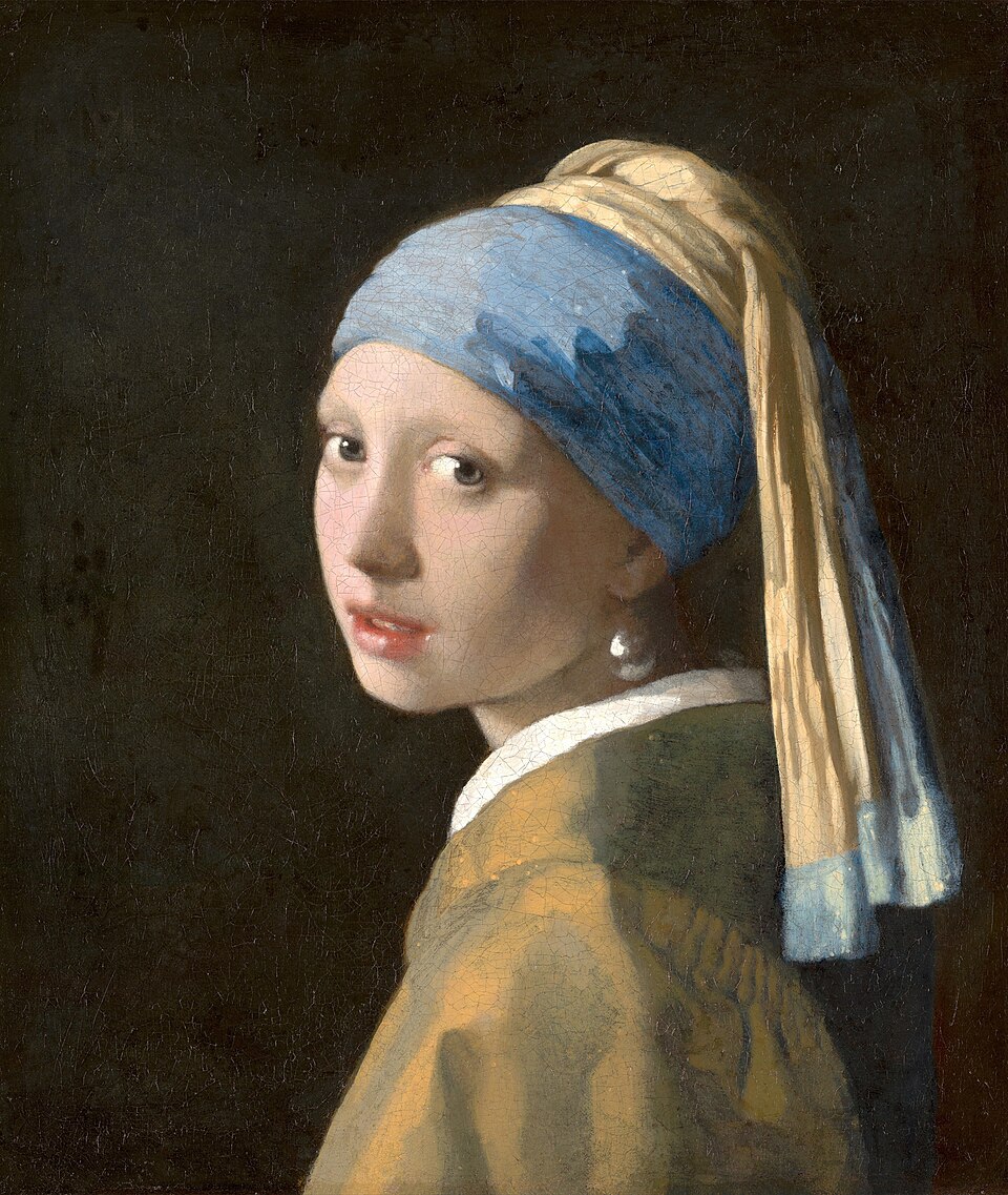 A young woman in a blue and yellow head covering turns toward the viewer, wearing a pearl earring.