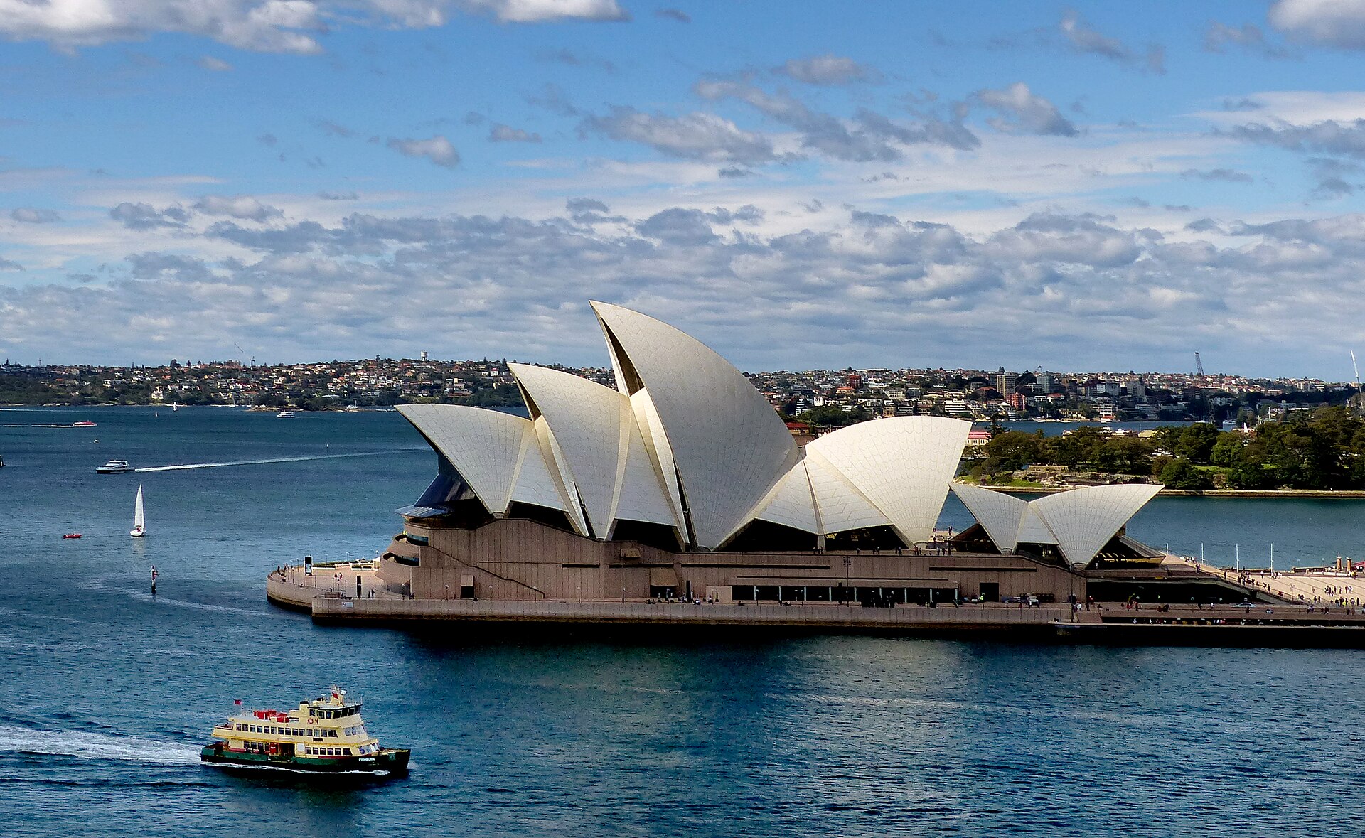 Sydney Opera House roof shells reflected along the harbour waterfront.