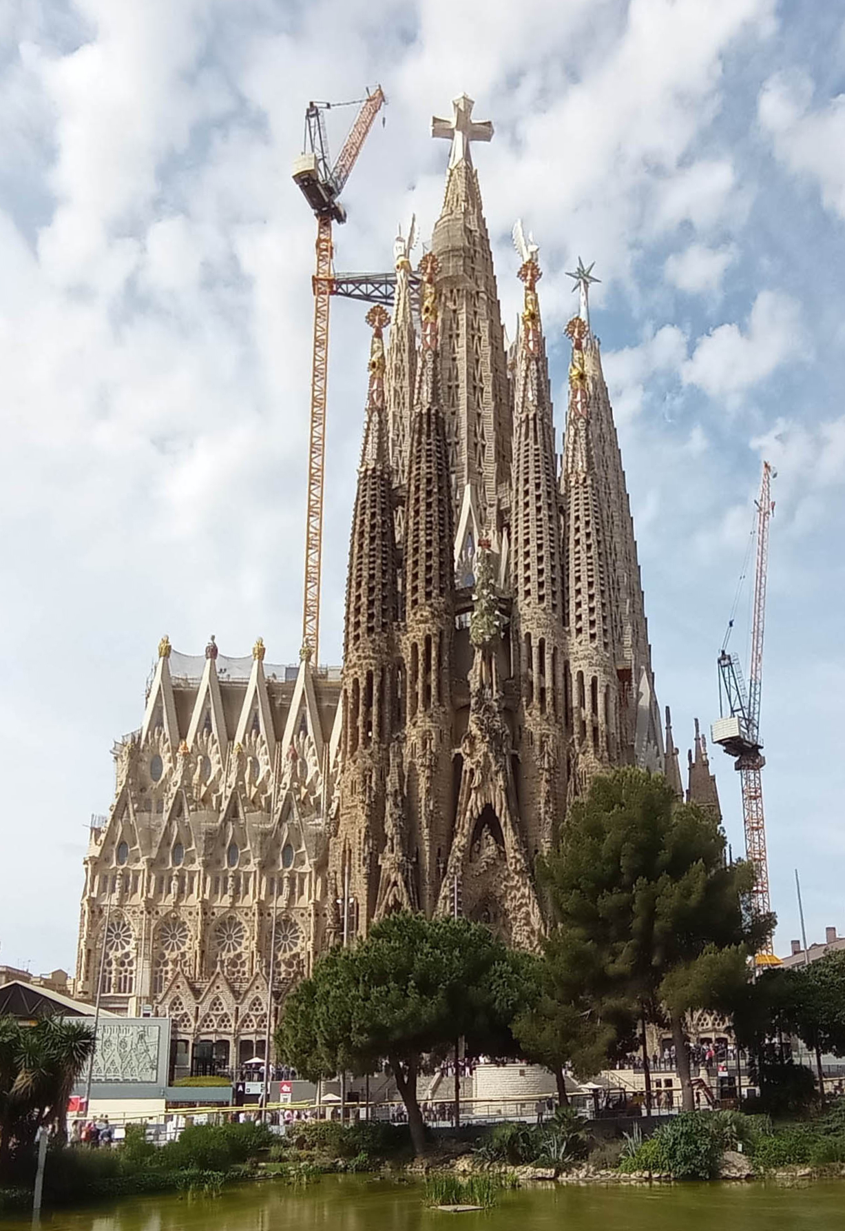Sagrada Família spires and decorated facade, seen from ground level.