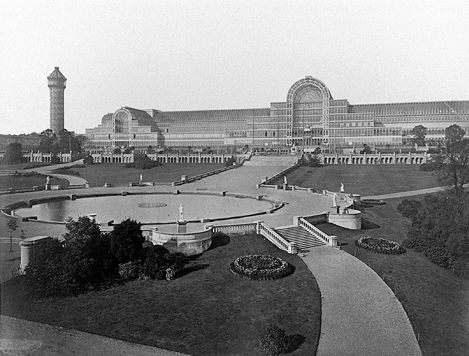 Black-and-white historical view of the Crystal Palace with paths and lawns in the foreground.