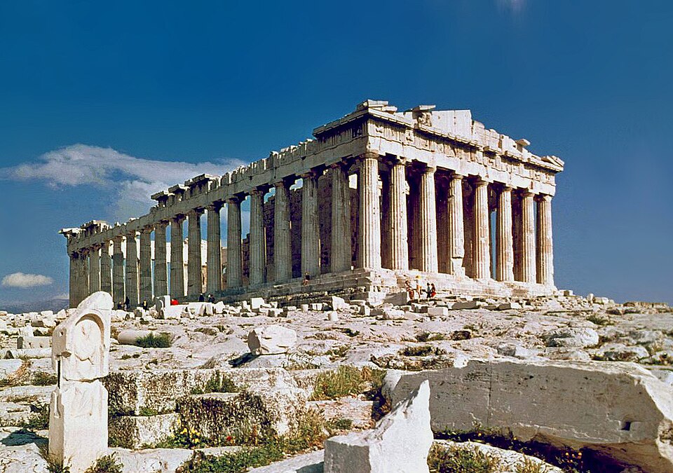 The Parthenon columns and entablature on the Acropolis against a blue sky.