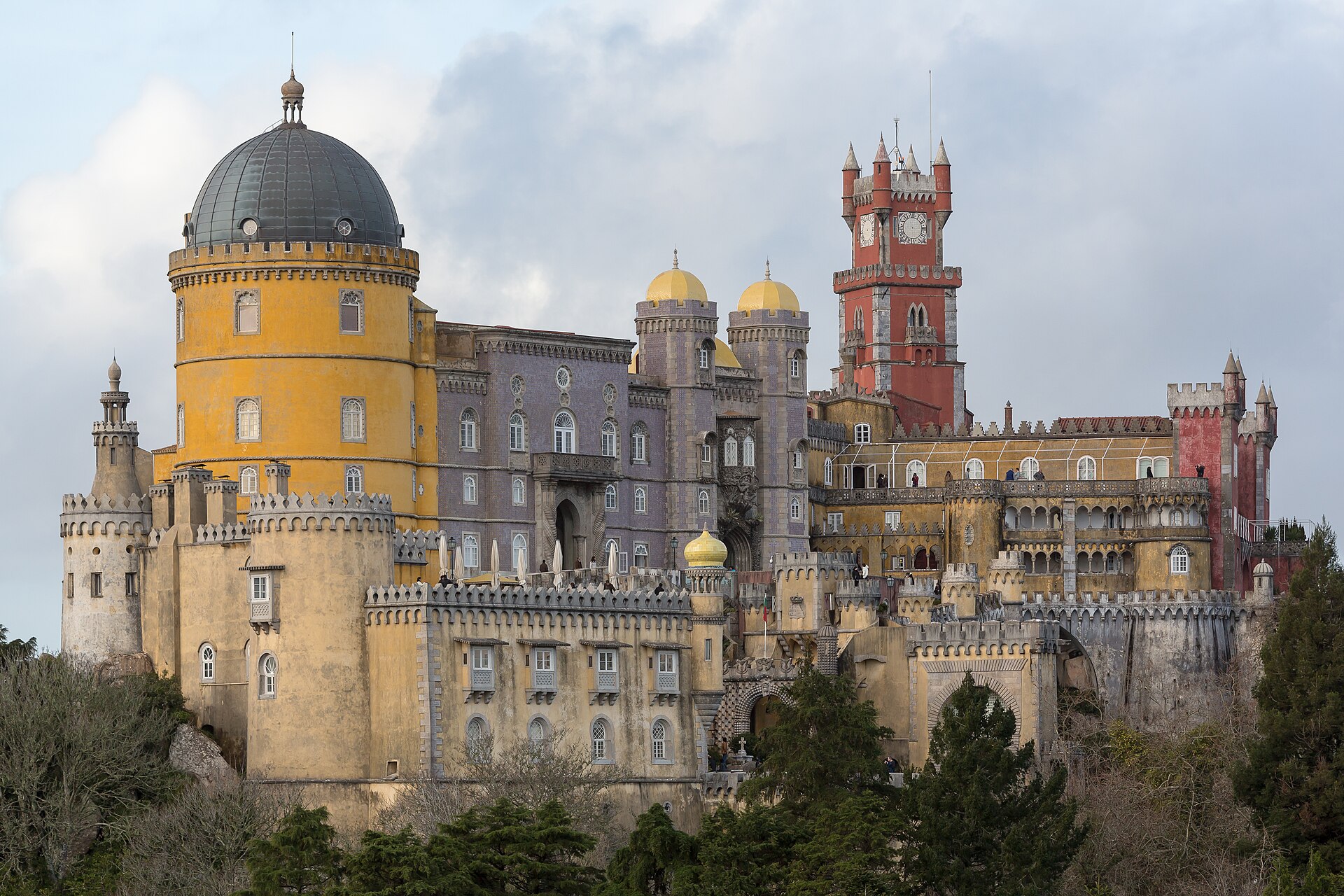 Colourful Pena Palace towers and walls seen above a hillside.